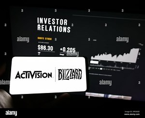 Person holding mobile phone with logo of US video game company Activision Blizzard Inc. on screen in front of web page. Focus on phone display Stock Photo - Alamy