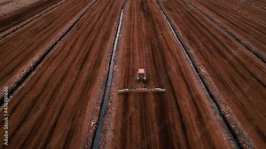Peat Harvester Tractor on Collecting Extracting Peat. Mining and harvesting peatland. Area drained of the mire are used for peat extraction. Drainage and destruction of peat bogs.