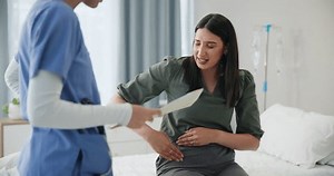 Doctor, patient and woman in a consultation, injury and conversation with nurse and healthcare. Professional, appointment and medical with emergency and treatment with diagnosis and stomach pain