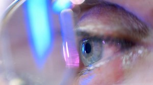 Reflection in the eye and glasses of the monitor screen when watching a movie. Closeup. Shallow depth of field
