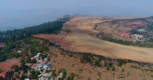 Drone footage of Table Land, Panchgani in the surroundings of Mahabaleshwar, Maharashtra, India, with a flat rocky plateau on top of a hill, the side is shaped like stairs and houses are built on it.