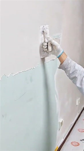 plastering the wall with a scraper to create a smooth surface while renovating the room interior