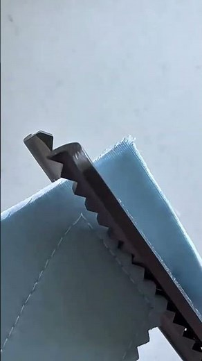 cutting light blue fabric material using pinking shears to create zigzag edges in a sewing project