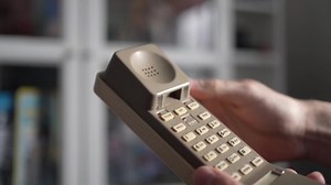 Using a old retro portable telephone from the 90s or 80s to place a call. Close-up of the brick phone being used