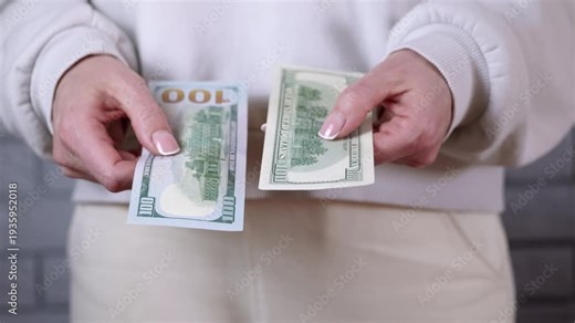 Woman comparing new and old hundred dollar bills. Hands of a woman comparing the new and old designs of the one hundred dollar bill, highlighting the differences in security features