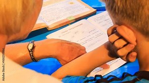 closeup backside woman teaches boy write in ABC work book