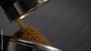 Grinder making coffee powder grinding aromatic beans in filter holder close up.