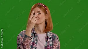 I am watching you gesture shown by Caucasian woman pointing at her eyes and camera on green screen background. Casual dressed female spying on someone.