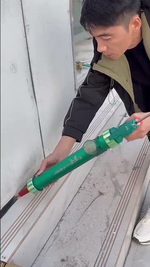 Applying sealant or caulk to the joint between wall and floor using a caulking gun