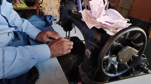 A closeup of an Indian tailor sewing clothes on an old sewing machine