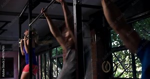 Three people doing chin up exercises on a pull up bar in a gym