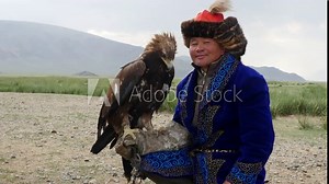 Kazakh Eagle Hunter in traditional clothing holding a golden eagle on his arm near Bayan-Olgii in West Mongolia.