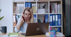 Blonde attractive office manager is calling on smartphone consulting a customer explaining services talking while working at corporate company.