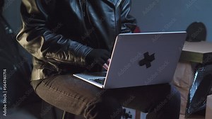 Criminal wearing bandit mask typing on laptop, then closes it and puts it away.