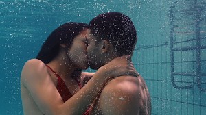 Young couple kissing underwater in swimming pool enjoying intimate kiss romantic lovers submerged in water floating with bubbles in passionate intimacy | Premium Stock Video Footage