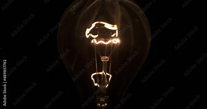 Glass light bulb and smoke from a burning spiral on a black background. The spiral of a light bulb is smoking inside a glass bulb Stock Video
