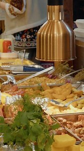 Vertical Screen Traditional Romanian street food served by a chef wearing a Romanian folk costume at a Christmas market