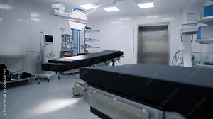 Dolly shot of operation block in modern clinic with advanced equipment ready for surgery. Operating table, LED lamps, life support machine. Bright operating room in hospital or medical facility.