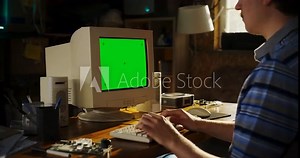 Zoom In Shot Of Caucasian Male Engineering Student Writing Thesis On Old Computer With Green Screen Chromakey On Display In Retro Garage. Engineer Focused On Project For Tech University In Nineties.