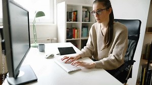 Focused young woman working on desktop PC. Young businesswoman working on computer at her home office