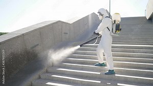 Disinfection against COVID-19 virus. professional disinfector in protective clothing fight with pandemic health risk, remove bacterias and infections using spray. outdoors.