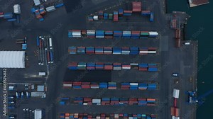 Aerial birds eye overhead top down view of stacked containers in harbour. Rows of various colour containers for overseas shipping. Logistics, import and export concept.