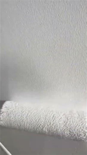 painter carefully applying fresh white paint using roller