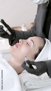 beautician hands in sterile gloves using dermapen during skincare procedure. Young woman receiving facial treatment in beauty salon. Concept of skincare and collagen induction