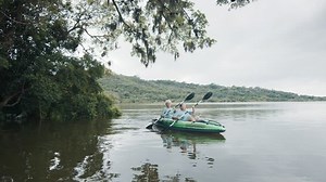 Senior women kayaking. Two elderly women paddle kayak on the fresh water lake with mangroves and trees. Elderly ladies enjoy kayaking on the calm lake at sunny day
