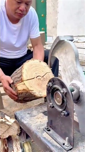 Man Using an Electric Saw Machine to Cut a Large Wooden Log into Smaller Pieces for Carpentry Work