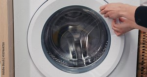 Close-up of hands trying to open the door of the washing machine, which is jammed broken. Anger, upset over a laundry problem.
