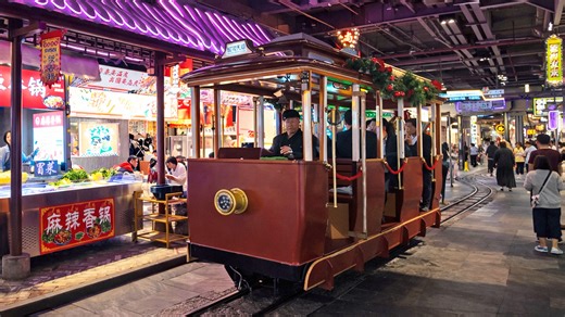 A vintage train moves through a busy underground mall