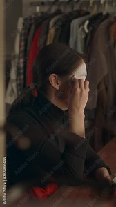 Vertical shot of female mime artist sitting in dressing room and applying white paint to face while doing stage makeup
