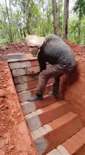 Man digging underground swimming pool in wild terrain, carving steps, water filling naturally