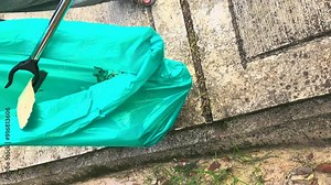 Picking up an up an old plastic bottle in the drain using a trash picker. 4K