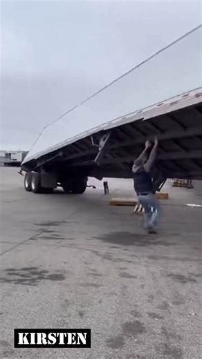 Raw phone footage in an industrial yard captures a heavy trailer slowly leaning beyond control. A quick attempt to steady it fails, and the moment ends with a loud collapse. | Kirsten Vaughn