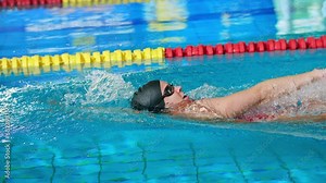 Slowmotion of female swimmer swimming in the indoor pool, training for competitive event backstroke, slow motion shot. Concept of back crawl swimming style.