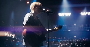 Indie Band Performing Live on Stage, Bringing Their Unique Sound to a Packed Club. Lead Singer Playing Acoustic Guitar with Passion and Energy. Stage Surrounded by Cheering Fans Holding Flashlights