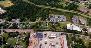 An industrial metal recycling and scrapyard that has train tracks beside it with a railroad siding that goes deep inside the recycling yard.