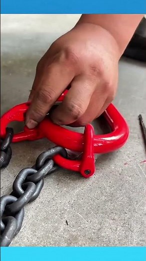 Securing the heavy chain onto the red shackle with tight, steady fastening for safe lifting.