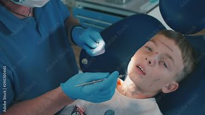 the dentist removes plaque from the child’s teeth during dental treatment