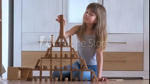 Creative child girl playing with jenga game stacking wooden toy blocks in high building structure. Hand movement control and concentration skills concept