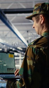Vertical video Military technician in data center tracking satellite coordinates using notebook software interface. Army unit in server hub analyzing reconnaissance data through satellite imaging