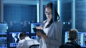 「若い女性エンジニアは、System Control Centerでタブレットを使用します。背景には、彼女の同僚がワークスペースにいて、多くのディスプレイが貴重なデータを表示しています。RED EPIC-W 8Kヘリウムシネマカメラで撮影」の動画素材（ロイヤリティフリー）26262245 | Shutterstock