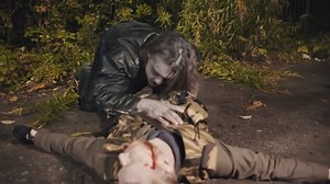 Zombie eating dead man lying on ground outdoors. Infected monster crawling out of bushes and biting corpse of young man lying on road. Halloween concept