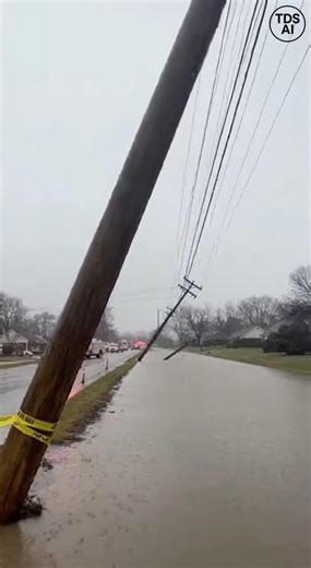 Storm-damaged power line falls into floodwaters, triggering visible electrical surge Shreveport, Louisiana — Video recorded in the aftermath of a powerful storm in Shreveport shows a damaged power line collapsing into rising floodwaters, sparking a dramatic electrical surge. The footage captures fast-moving water covering portions of a residential street when a sagging utility line suddenly gives way. As the live wire makes contact with the floodwater below, bright flashes and crackling sounds e