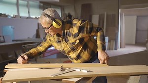 Wood Board Measurement in a carpentry shop. Male carpenter measuring wood with meter and marking with pencil.
