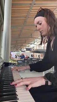 Girl is playing a public piano while people watch in awe!