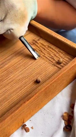 carving wood surface with a gouge to create repetitive textures and details on a wooden tray