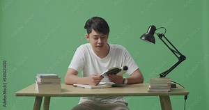 Young Asian Male Reading Books While Studying On Green Screen Background At Home Stock Video